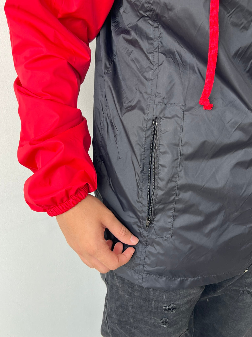 Chaqueta cortavientos SOUTH roja con negro, detalle de bolsillo con cierre y puno elastico
