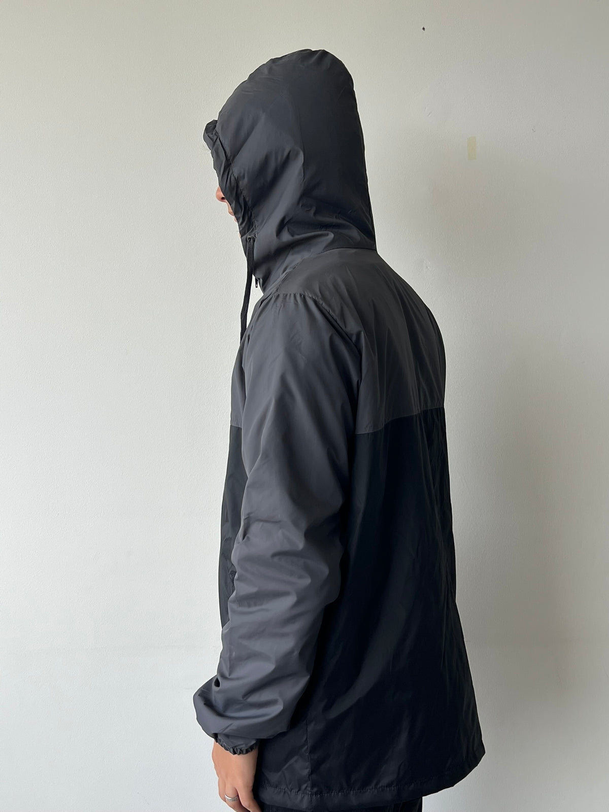 Chaqueta cortavientos SOUTH gris con negro, vista lateral con capucha puesta